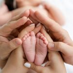 تصویر پای نوزاد با دستان پدر و مادر