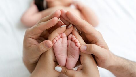 تصویر پای نوزاد با دستان پدر و مادر