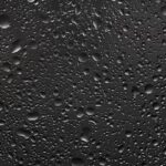 تصویر مجموعه قطرات باران و آب روی شیشه تیره