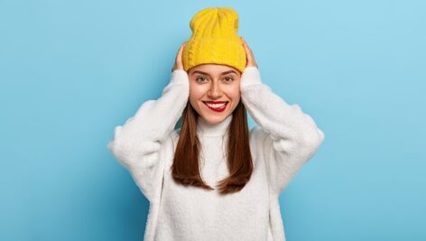 تصویر زن جوان خوشحال با کلاه زمستانی و ژاکت