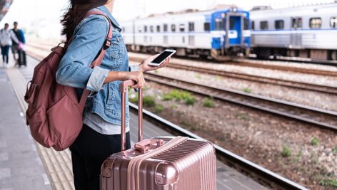 تصویر پس زمینه دختر جوان با چمدان در ایستگاه قطار