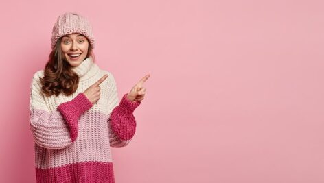 تصویر زن جوان با لباس زمستانی و اشاره کردن