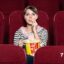 تصویر دختر جوان در سینما در حال فیلم دیدن