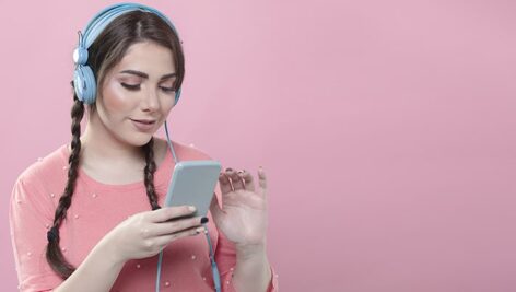 تصویر زن جوان با هدفون و موبایل و گوش دادن به موسیقی